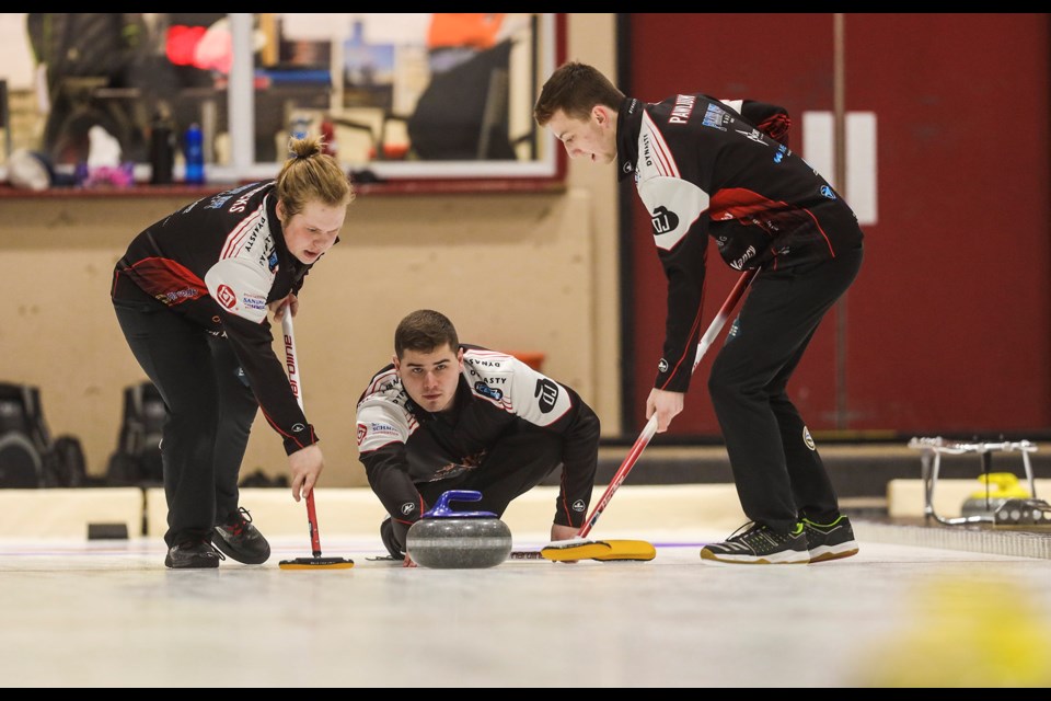 Team Libbus second Michael Henricks, left, and lead Zachary Pawliuk, right, take over sweeping a throw by skip Jacob Libbus during the the Alberta Junior Curling qualifiers at the Oilfields Curling Club on Dec. 7. (BRENT CALVER/Western Wheel)