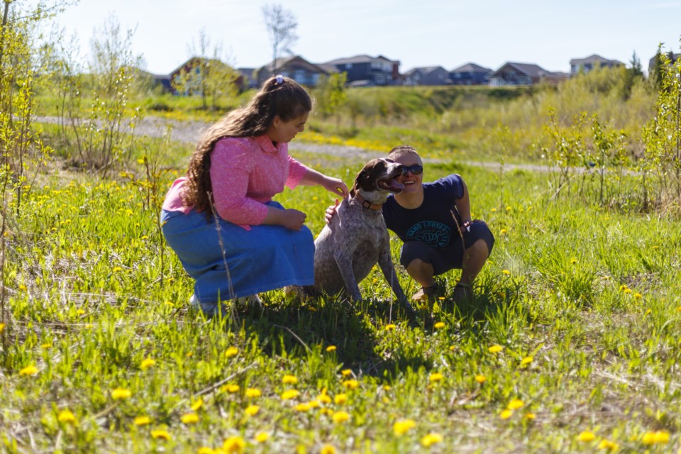 Conrad Graup and Susanna Kiffiak pet Graup’s dog Buck near Oilfields High School. (Photo by Devon Langille)