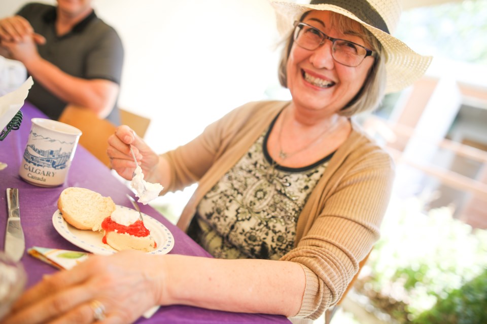 Virginia Battiste of Black Diamond dollops cream on a scone at the Millarville Flower Festival at the  Christ Church Millarville  in 2018. (Brent Calver/Western Wheel)