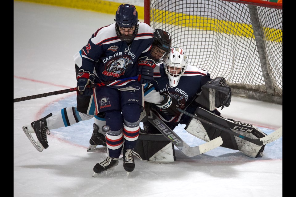 Carstar Okotoks Bisons defenceman Avery Greig blocks a shot in front of goalie Dylan Walker and Sylvan Lake Wranglers forward Aydden Shaw during Game 2 of the best-of-five Heritage Junior Hockey League Final on March 23 at the Murray Arena.