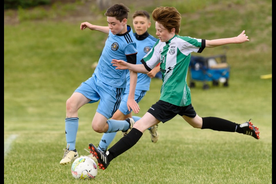 Jacob Allen, right, with Okotoks United, moves the ball towards the goal against Blizzard SC12 player Zachary Lambert in boys Tier 2 U13 first-round play in the OUSC Jamboree in Okotoks in June 2024. 