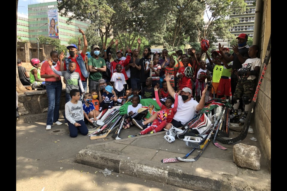 Jamie Shand, father of Rocky Mountain Raiders forward Isobel Pettem-Shand, with a group of young hockey players in Kenya and the donations of hockey equipment collected by the Raiders in January.
(Photo submitted)