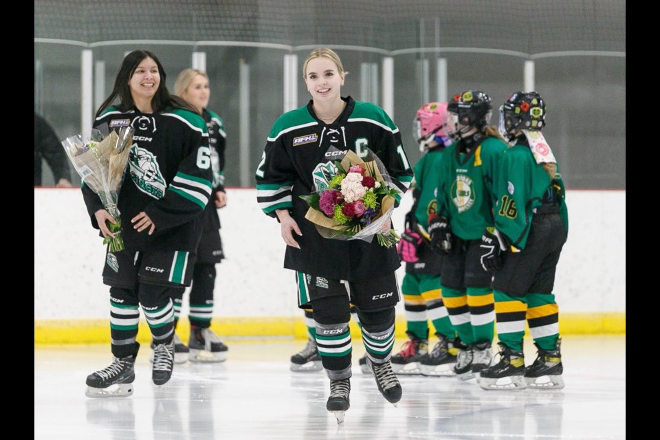 Rocky Mountain U18 AA Raiders graduating players Rozene Sabeti-Seidel, left, and Grace Bjornson skate off the ice after a ceremony recognizing the team’s graduating players in its regular season home finale versus Calgary on Feb. 25 at the Scott Seaman Sports Rink.