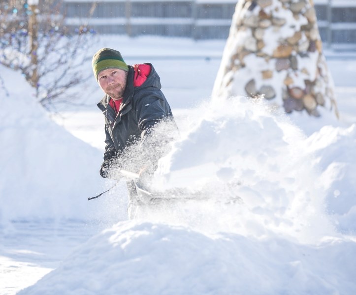 Ryan Penner clears his driveway of snow at Robinson Dr. after a winter storm in December. Environment Canada has issued a winter snowstorm warning in the Foothills, with as