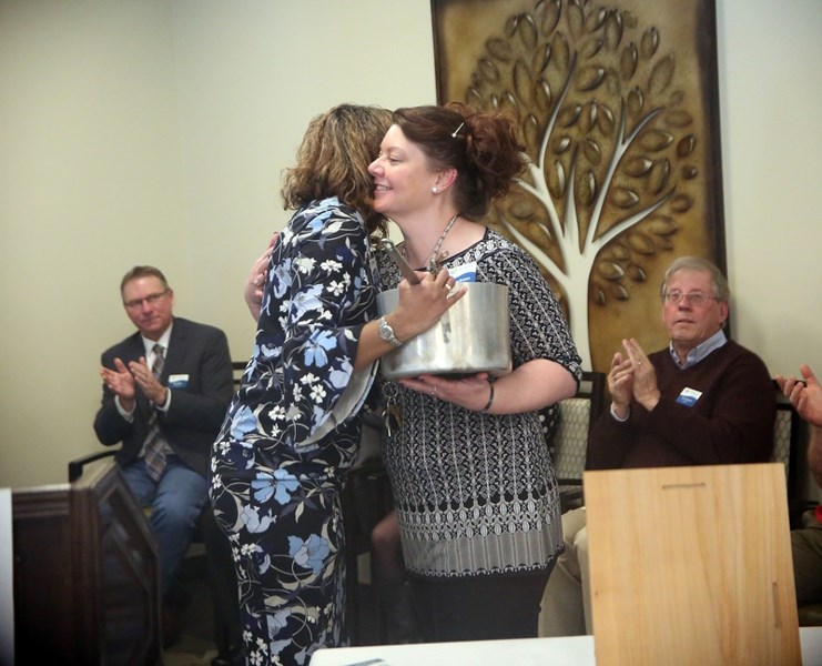 Medicine Tree Manor program director Tanya Bristow, right, accepts a pot that survived the 2013 flood from Westwood Communities CAO Lauren Ingalls at the senior citizens