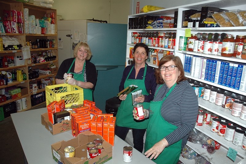 From the left, Okotoks Food Bank volunteers Sheila Rast, Carol Nerland and April Pitts help stock shelves at the food bank.