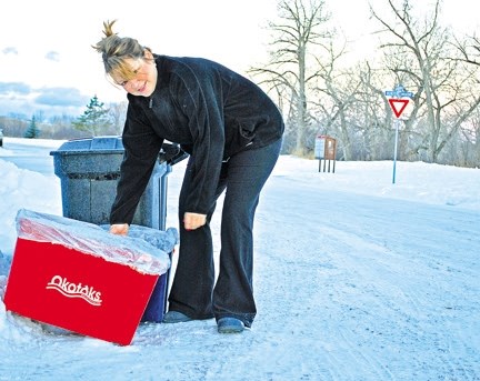 Gail Giroux, a resident of Hunters Place in Okotoks, takes out her recycling early Monday morning. Giroux has been a Curb It subscriber since the program launched last