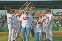Brian and Tammy Whitnack walk under a wedding arch of baseball bats during their wedding at Seaman Stadium on July 24, 2009. The couple is happily married and living in