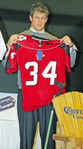 Calgary Stampeder and Olympic bobsledder holds up an autographed Calgary Stampeder jersey being auctioned at the Okotoks Dawgs awards banquet Saturday night at the Foothills