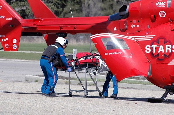 STARS Air Ambulance personnel load a youth who was injured when he ran into a car while riding his skateboard on Woodgate Road in Okotoks.