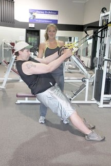 Personal trainer Clare Russell of Big Rock Training and Fitness helps Mike Fotie with his workout on a TRX band last week. Russell was voted the Best coach/trainer in the