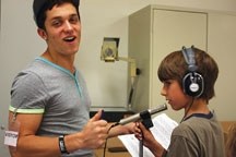 Musician Connor James left, helps Percy Pegler School student Micah Lyons prepare to record his portion of a song in honour of Alberta&#8217;s historical mavericks. The tune