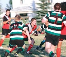 Foothills Lion Dustyn Peterson braces himself for contact with several Calgary Saracens in hot pursuit during the first half of Calgary&#8217;s 15-12 win Aug. 26 at John Paul 