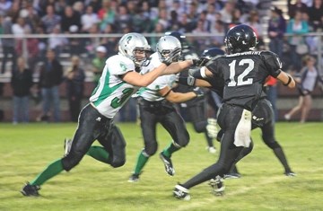 Foothills Falcons quarterback Taylor Armsworthy (right) tries to escape a ferocious pass rush from the Holy Trinity Academy Knights&#8217; defence during the third quarter of 