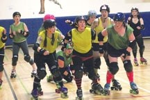 Jammer Desiree Brook, in yellow jersey and striped socks, crashes through some blockers to score some points at a Foothills Roller Derby Association scrimmage on Jan. 29 in