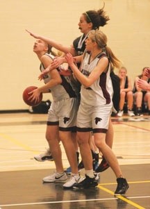 Foothills Falcon Kalli Turbach (left, white shoes) prepares to go up for a shot against the George McDougall Mustangs on March 9. Her twin sister, Madie (black shoes, right)
