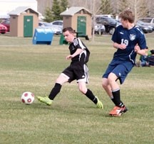 Holy Trinity Academy Knights&#8217; striker Tyson Fedor (left) works around Notre Dame Collegiate in Foothills Athletic Council action, April 25 at Riverside Park in Okotoks.
