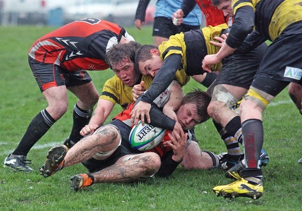 Foothills Lion Steven Jones latches onto the ball from a trio of Calgary Hornets during the Division II Lions&#8217; 12-0 loss to the Hornets, Mar 5 at the Calgary Rugby