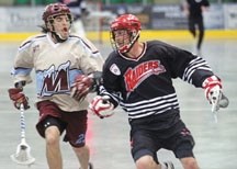 Okotoks Raider Carson McCormick protects the ball from hard-charging Calgary Moutaineer Tyler Melnyk durind the Raiders&#8217; 10-9 win, May 9 at the Okotoks Centennial Arena.