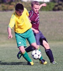 Foothills Composite Falcons midfielder Anthony Pearse, right, tackles a Canmore Crusader during a Foothills Athletics Council game May 28 at Kinsmen Field in Okotoks.