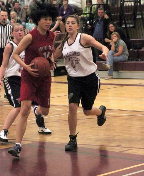 Foothills U-16 Falcon Jocelyn Skrilec (right) and Jenna Thomson converge on a South Korean player in an exhibition basketball game on June 6 in Okotoks.