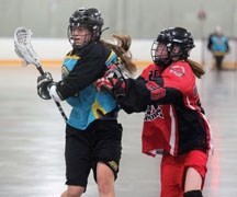 Okotoks Mustang Ally Bymak fights through a crosscheck from an Edmonton Warrior and fires a shot during the Bantam Girls Provincial championship, June 29 at South Fish Creek
