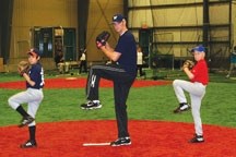 Jim Henderson, now a member of the Milwaukee Brewers, helps two young members of the Okotoks Outlaws in 2009. Henderson has worked with several of the Foothills Black