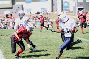 Foothills Eagle running back Jeus Mapatac (14) prepares to go around a Calgary Stampeder at the Bantam Football Jamboree on Aug. 26 at Holy Trinity Academy in Okotoks.