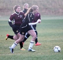 Holy Trinity Academy Knights&#8217; striker Brooklyn Smith surveys her options as Foothills Falcon Micah Wiltse rushes back to defend during the Knights&#8217; 4-0 win in the 