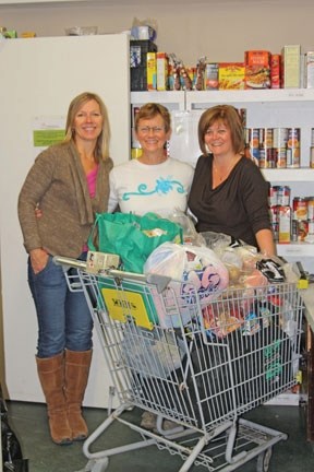 Okotoks Food Bank Executive Director Karen Wilke and volunteers Colleen Smith and Karen Molvik prepare a food hamper for a family of one adult and four children at the United 