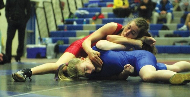 Foothills Falcon Cassidy Barnert, here wrestling Holy Trinity Academy Knight Jenna Morrison in High River on Feb. 22, won the gold medal at the Alberta high school wrestling