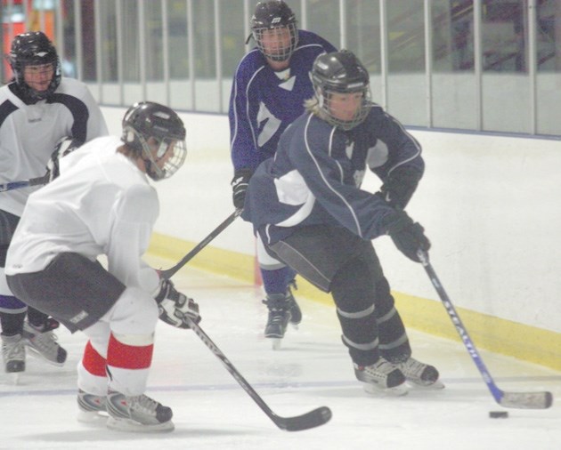 Neilly McDougall, right in blue, stickhandles her way around a teammate during a Okotoks Rockies practice on March 28. The team, consisting of many Okotoks hockey moms, won