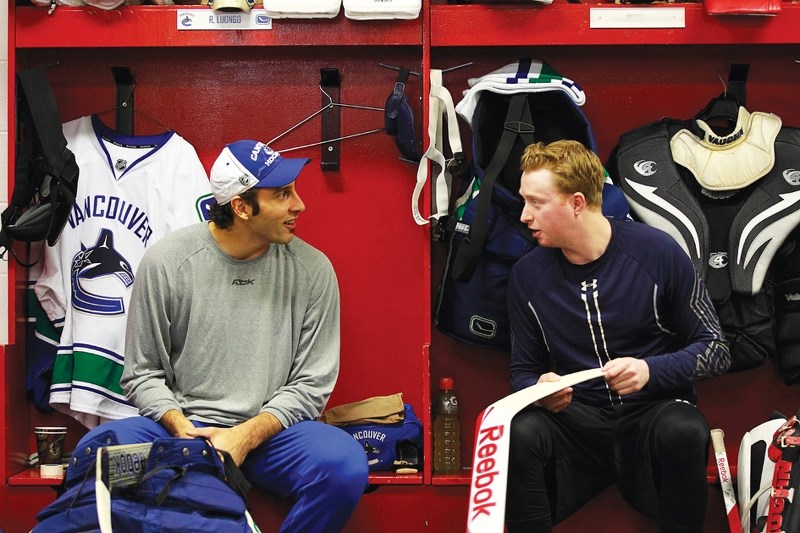 Vancouver Canucks goalie Roberto Luongo (left) chats with University of Calgary Dinos netminder Dustin Butler in the visitors dressing room at the Calgary Saddledome prior to 