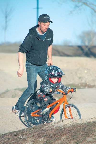 Ken McAlister of the Okotoks BMX Club helps a youngster get through the Okotoks track.