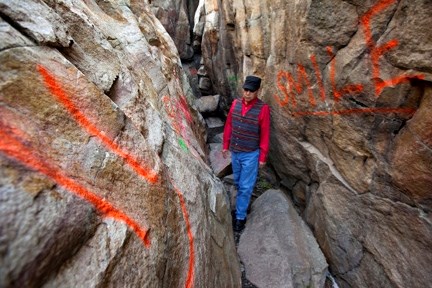 Blair First Rider, Aboriginal Consultation Advisor with the provincial governments Heritage Division, walks through a crevice littered with spray painted graffiti at the Big