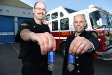 Okotoks firefighters Ryan Kaiser and Adam McInnis present their medals for 12 years of service on May 21 at the Okotoks fire hall.