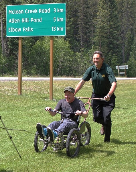Tourism, parks, and recreation minister Richard Starke pushes volunteer Stephen Henry in the new Park Explorer backcountry wheelchair.