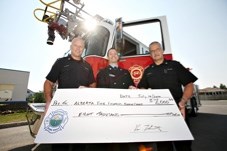 Okotoks Fire Chief Ken Thevenot, right, and firefighter Bob Button, left, donate $8,000 to Ian McKee, with the Edmonton chapter of the Firefighters Burn Treatment Society to