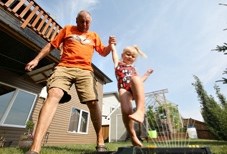 Turner Valley resident Merv Page and his three-year-old granddaughter Amelia Myles jump through a sprinkler in his backyard. The Towns of Black Diamond and Turner Valley