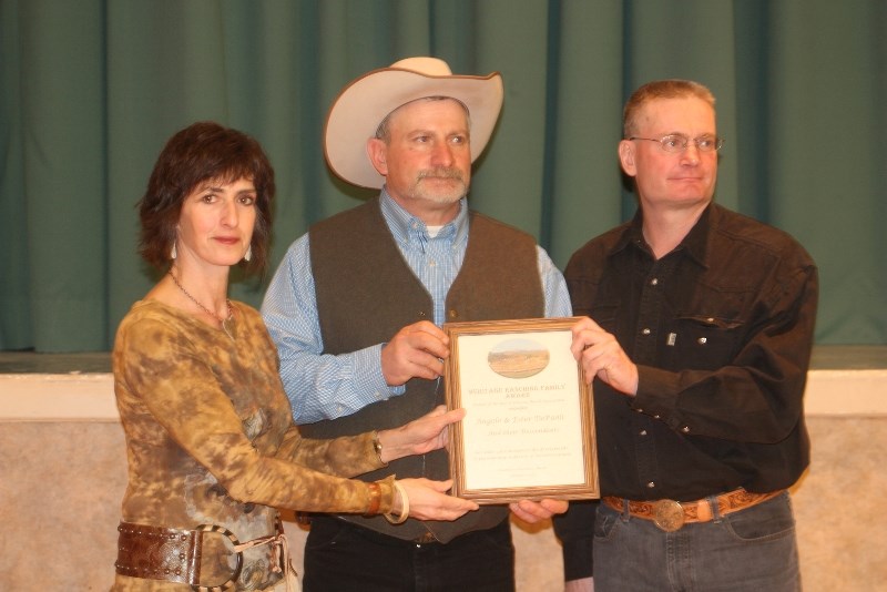 Avril Chattaway, president of Friends of the Bar U Historic Ranch Association, presents brothers Lorne and Angelo DePaoli with a plaque to honour their grandparents Angelo