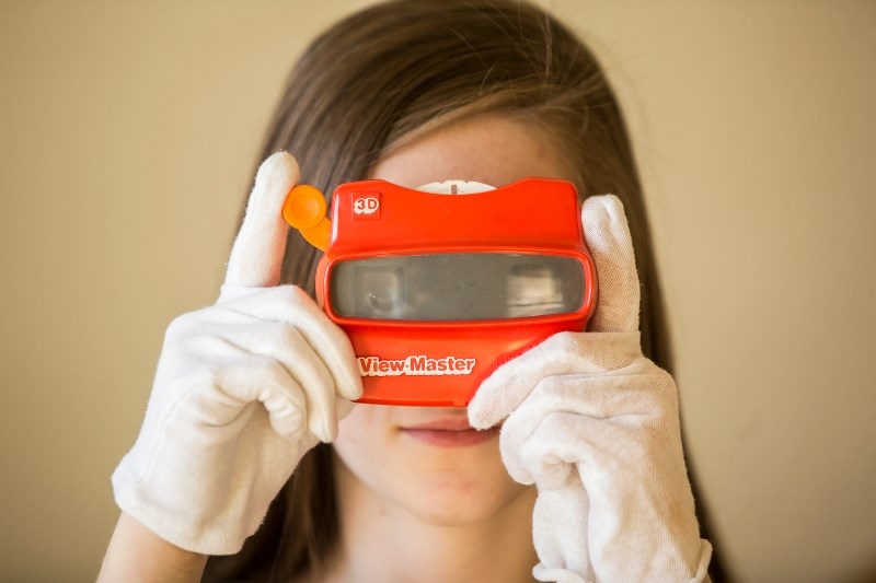 Student volunteer Abby Sauerwein plays with a View-Master, an interactive part of the Canada at Play exhibit at the Okotoks Museum and Archives on Nov. 4.