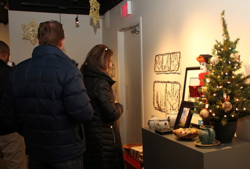 Mara Wortley stops to look at a painting during the opening reception of the Spirit of Christmas exhibit at the Okotoks Art Gallery on Nov. 14.
