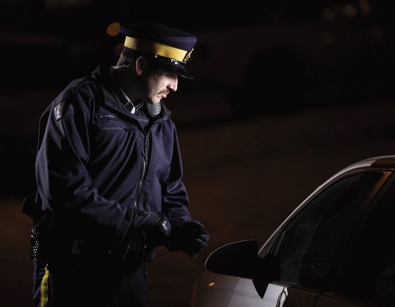 Okotoks RCMP Const. Mark Gander leaves cards informing residents to lock their cars at night.