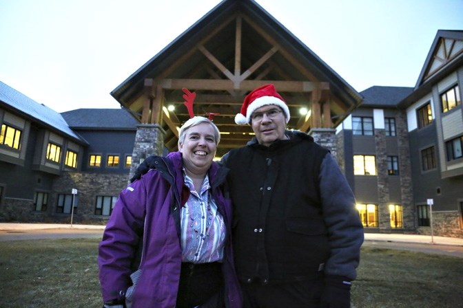 Grant Sullivan and his wife, Silvia Corsini, lead a group of volunteers through Tudor Manor to sing carols on Christmas Day. The couple is seeking volunteers for this