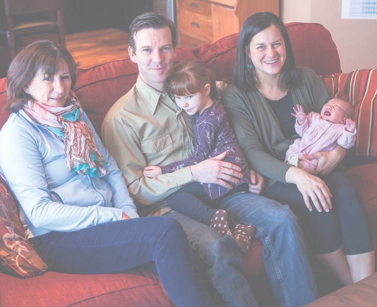 Proud parents Brigitte Legault and Dylan Kunz, rest in their home Jan. 5 with their newborn baby girl, Mercedes, daughter Felicity, midwife Marie Wilkinson, far left.