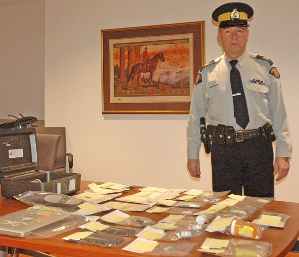 Okotoks RCMP Staff Sgt. Jim Ross stands beside a table covered in $6,000 drugs seized after a month-long drug investigation.