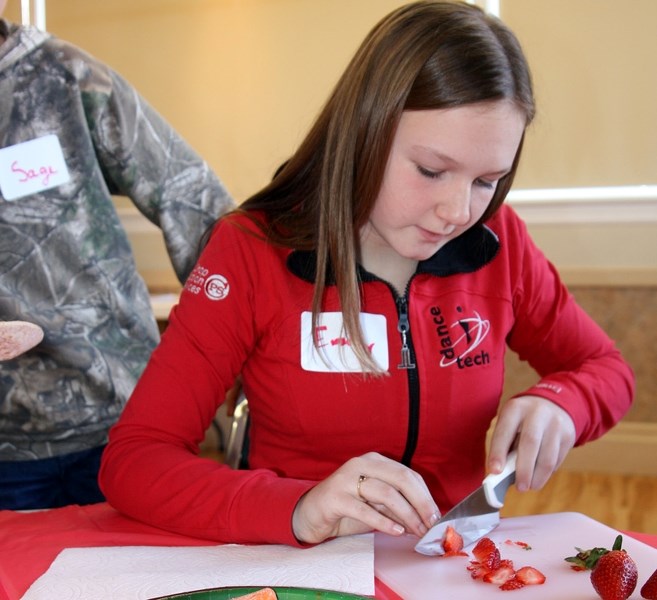 Emily Anderson, a Grade 7 student at Cayley School, slices a strawberry at the Cutting Edge – healthy eating seminar during the Healthy Active School Symposium in High River