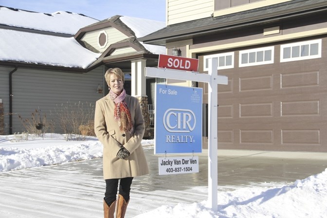 Jacky van der Ven stands outside an Okotoks home she recently sold in Cimarron. She says the buyer&#8217;s market is not all &#8216;doom and gloom&#8217; but cautions sellers 