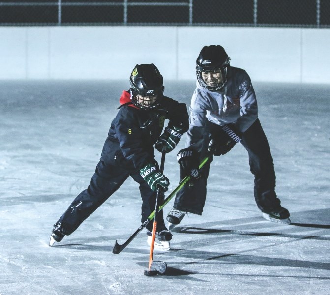 Eight-year-old Vance Amyotte battles his mom, Gaylene, for the puck at the outdoor rink in Black Diamond on Jan. 15.