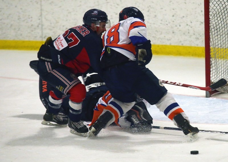 Okotoks Bison Kyle Becker digs for a rebound versus High River Flyers captain Cole Miller during the Bisons&#8217; 6-4 win on Jan. 24 at Murray Arena. The victory clinched